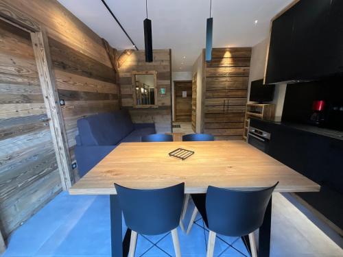 a dining room with a wooden table and blue chairs at Gite Roche Des Ducs avec Piscine toute l'année, Spa, Sauna, Hammam in Rochesson