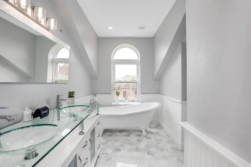 Baño blanco con bañera y lavamanos en The Lumber Baron's Penthouse 3BR / 2.5 BA en Detroit