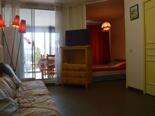 - une chambre avec une télévision sur une commode et un lit dans l'établissement Appartement cosy 2 pièces avec terrasse fermée, proche plage et commerces, parking privé inclus - FR-1-250-156, au Grau-du-Roi