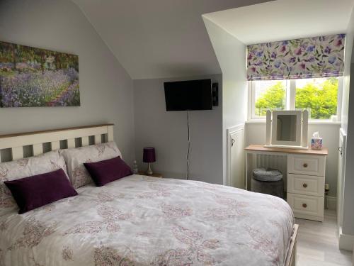 a bedroom with a bed with purple pillows and a tv at Laurel Lodge in Droichead an Chaisleáin