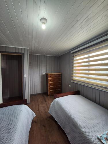 a bedroom with two twin beds and a window at Cabañas Roma in Valdivia