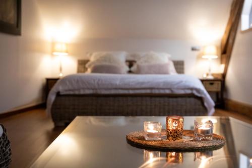 Un dormitorio con una cama y una mesa con velas. en Duo Détente, en Le Chenoy