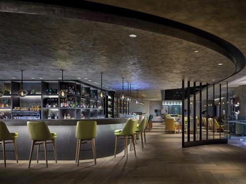 a restaurant with green chairs and a bar at Cordis, Hong Kong in Hong Kong