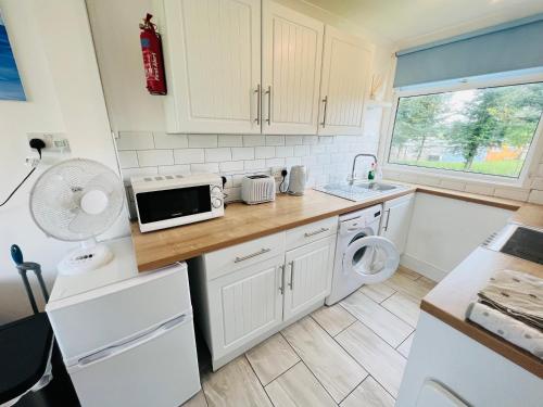 a kitchen with white cabinets and a washer and dryer at 2 Bedroom Chalet SB22, Sandown Bay, Isle of Wight, Dog Friendly in Sandown