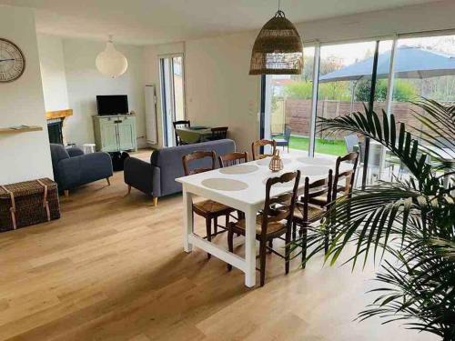 un salon avec une table et des chaises blanches dans l'établissement Maison Pornichet -3 ch- Proche hippodrome, plages, à Pornichet