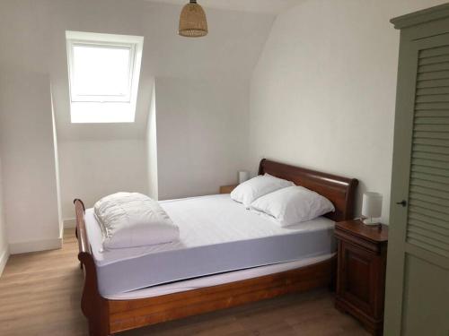 Cette chambre comprend un lit avec des draps blancs et une fenêtre. dans l'établissement Maison Pornichet -3 ch- Proche hippodrome, plages, à Pornichet