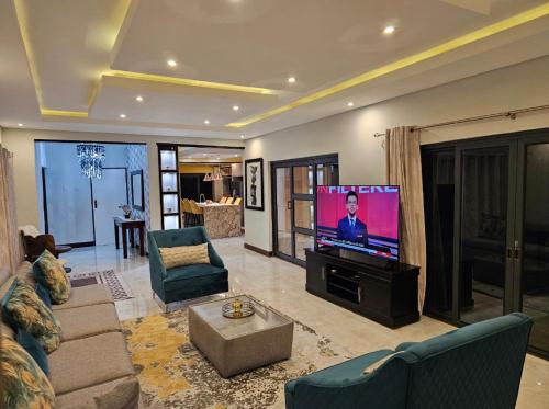 a living room with a tv and a couch and chairs at Chuumba Villas in Lusaka