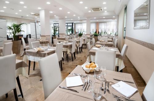 a restaurant with white tables and white chairs at Hotel Novella in Misano Adriatico