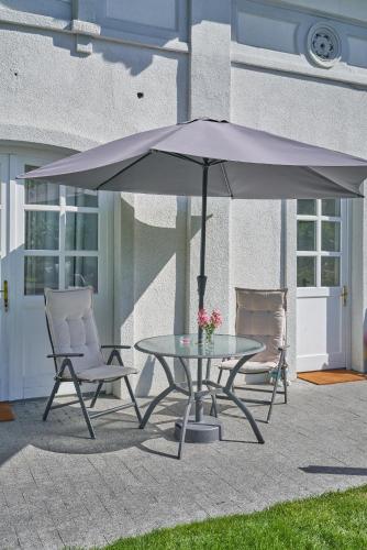 a table and chairs under an umbrella on a patio at Exclusive Entry: Cozy Guestroom in Baden