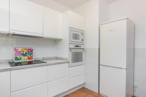 a white kitchen with white cabinets and a refrigerator at Finca Son Blat in Porto Cristo