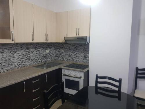 a kitchen with white cabinets and a sink and a stove at Fresk Area in Tirana