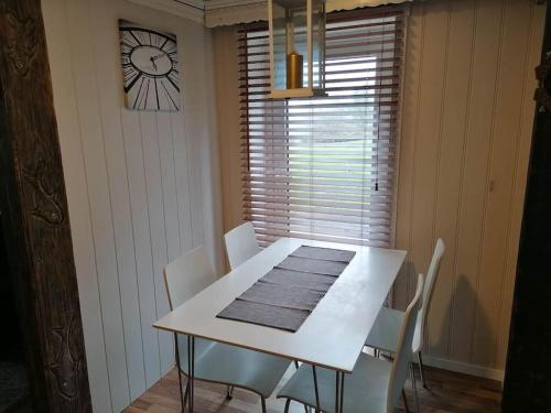 a dining room table with white chairs and a clock on the wall at Viltė Rest House 