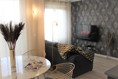 a living room with a table and a tv at Arty - Premium - Parking box privé - Balcon - Sauna en option in Saint-Priest