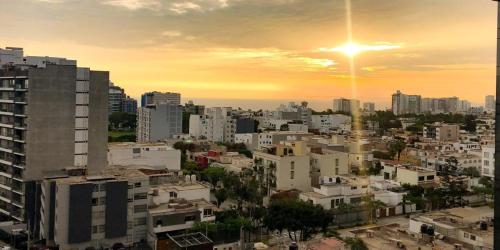 a city skyline with the sun setting behind buildings at Departamento Family in Lima