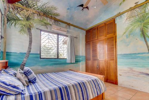 een slaapkamer met een muurschildering van palmbomen aan de muur bij Villa Maya Gold Standard and Certified in San Ignacio