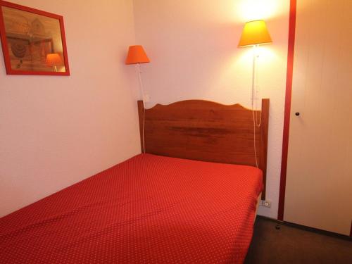 - une petite chambre avec un lit rouge et une lampe dans l'établissement Appartement cosy 2P pour 4 pers. à 100m des pistes et commerces - L'Alpe d'Huez - FR-1-405-212, à Huez