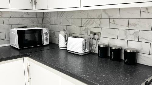 eine Küchentheke mit einer Mikrowelle und einem Toaster in der Unterkunft Comfortable Modern Bedroom Space with Ensuite near Bramall Lane Stadium and RHH in Sheffield