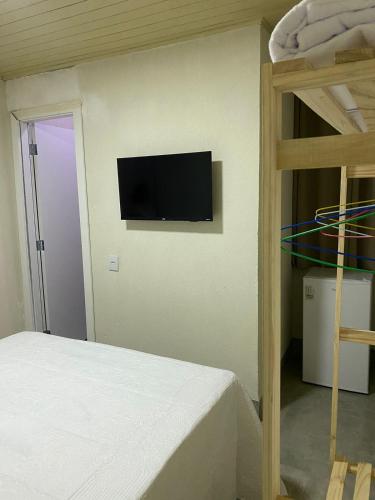 1 dormitorio con 1 cama y TV de pantalla plana en la pared en Hospedagens Express I, en Chapada dos Guimarães