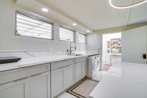 a white kitchen with a sink and a dishwasher at Breezy Honolulu Home Rental Ocean and Skyline Views in Honolulu