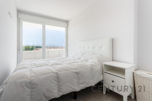 a white bedroom with a bed and a window at Apartamento de lujo con 2 habitaciones en Canet d'en Berenguer in Canet de Berenguer