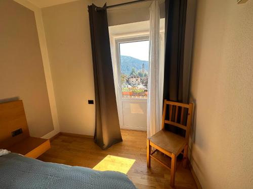 a bedroom with a bed and a chair and a window at Pippi Home in Castello di Fiemme