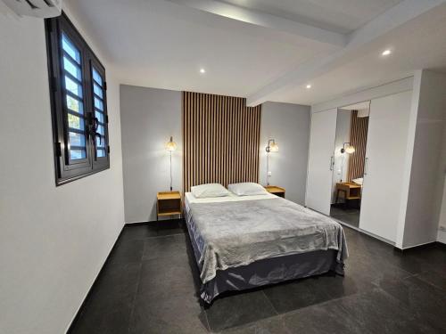 een slaapkamer met een bed, 2 tafels en een raam bij ECOLODGY Suites Villa in Ducos