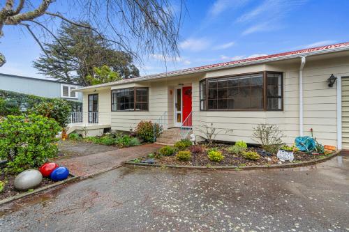 a white house with a red door at Central Comforts - Mount Eden Holiday Home in Auckland