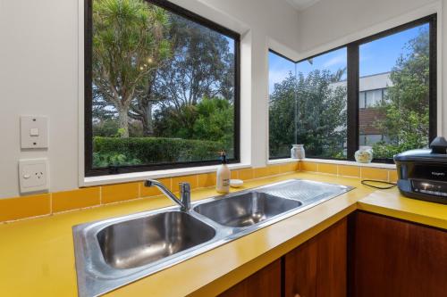 a kitchen with a sink and two windows at Central Comforts - Mount Eden Holiday Home in Auckland