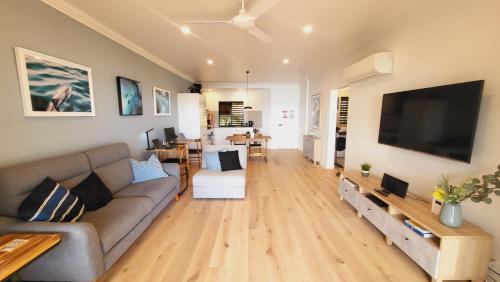 a living room with a couch and a flat screen tv at Luxury Couples Retreat Hamilton Island with Buggy in Hamilton Island