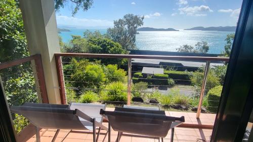 a balcony with chairs and a view of the water at Luxury Couples Retreat Hamilton Island with Buggy in Hamilton Island