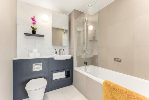 a bathroom with a toilet and a sink and a tub at Bloom of Luxury in London