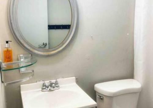 a bathroom with a white toilet and a mirror at Airport Xpress Guestrooms in Philadelphia