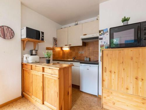 Il comprend une cuisine avec des placards en bois et une télévision murale. dans l'établissement Appartement T2 avec Balcon, Parking Privé et Proche Téléphérique à Saint-Lary-Soulan - FR-1-296-350, à Saint-Lary-Soulan