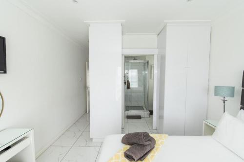 ein weißes Schlafzimmer mit einem Bett und einer Dusche in der Unterkunft Dolphins View Luxury Apartment in Port Elizabeth