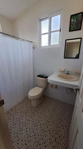 a bathroom with a toilet and a sink and a window at Casita del Arco El Cedral Cozumel in Cozumel