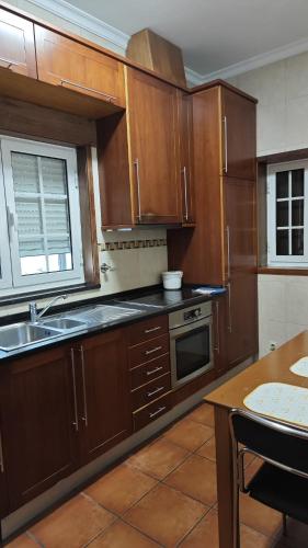 a kitchen with wooden cabinets and a sink and a table at AL Sr Domingos in Vila Verde
