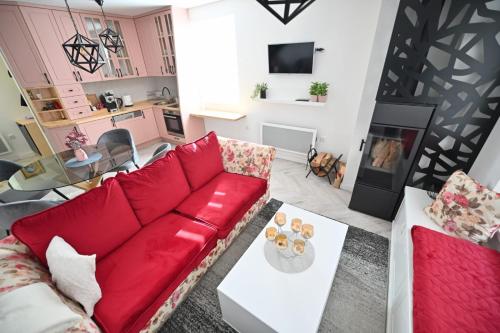 a living room with a red couch and a fireplace at Apartmani Dimitrije Jahorina in Jahorina