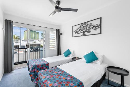 two beds in a room with a balcony at Villa Vaucluse Apartments in Cairns