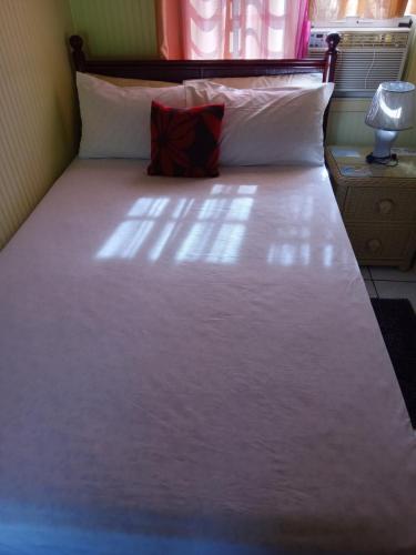 a bed with white sheets and a red pillow at Apartment Unforgetable Gardens in Falmouth