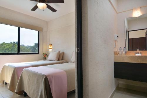 a hotel room with two beds and a sink at Hotel Coral Cuernavaca in Temixco