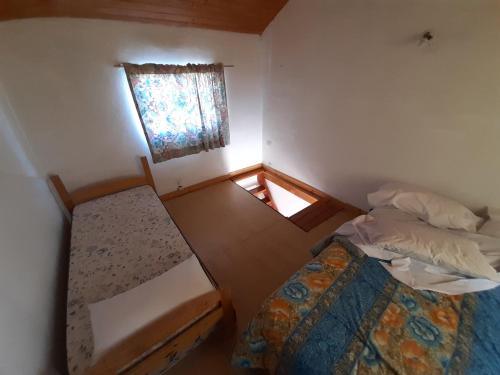 Habitación pequeña con 2 camas y ventana en Dptos Rio Neuquen en 