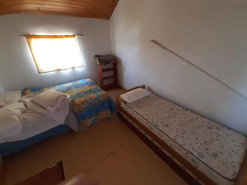 niewielka sypialnia z 2 łóżkami i oknem w obiekcie Dptos Rio Neuquen w mieście Huinganco