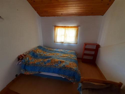 a small bedroom with a bed and a window at Dptos Rio Neuquen in Huinganco