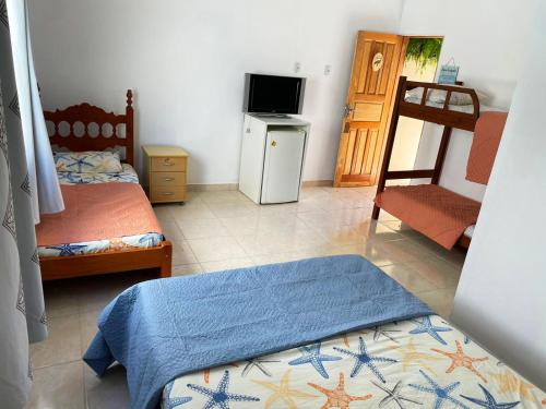 a bedroom with two beds and a tv and a chair at Casa Amarela Hostel in Guarapari