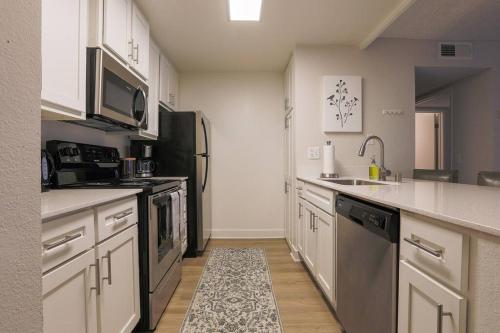 a kitchen with white cabinets and a black refrigerator at Shabby Chic Oceanside King & 2 Queen bed Pool GYM in Oceanside