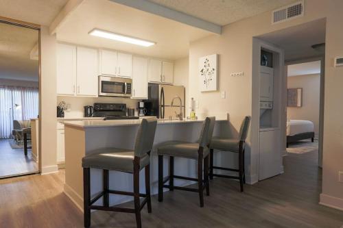 a kitchen and living room with a counter and chairs at Shabby Chic Oceanside King & 2 Queen bed Pool GYM in Oceanside