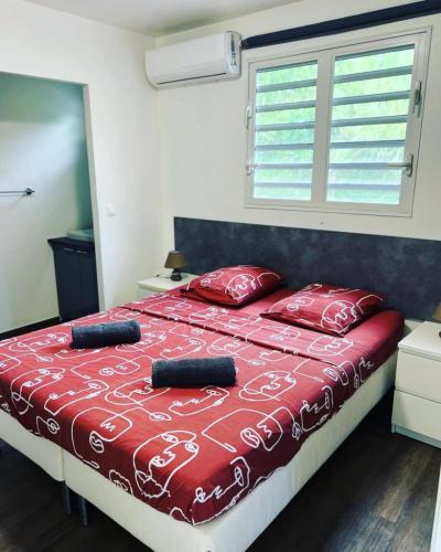a bedroom with a bed with red sheets and a window at Le domaine de Périolat in Le François