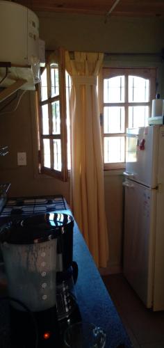 a kitchen with a stove and a refrigerator and a window at Cabañas RoFran in La Consulta