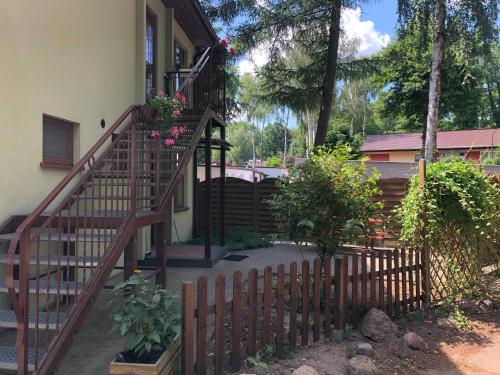 a wooden fence next to a house with a staircase at Domek pod świerkami 1 in Skorzęcin