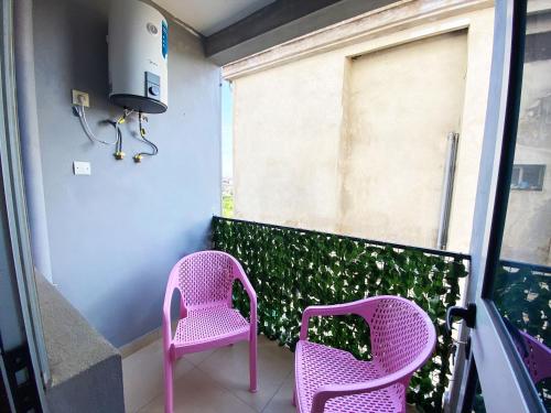 two pink chairs sitting on top of a balcony at Residence Atlantic - Premium Apartment - WiFi, Gardien, Parking, Climaté in Douala